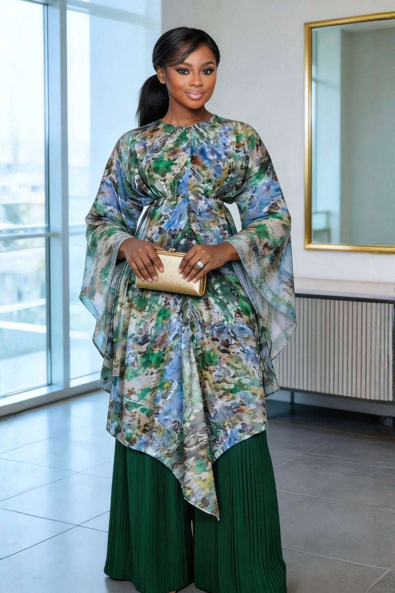 Woman in a floral dress holding a gold clutch in an indoor setting.