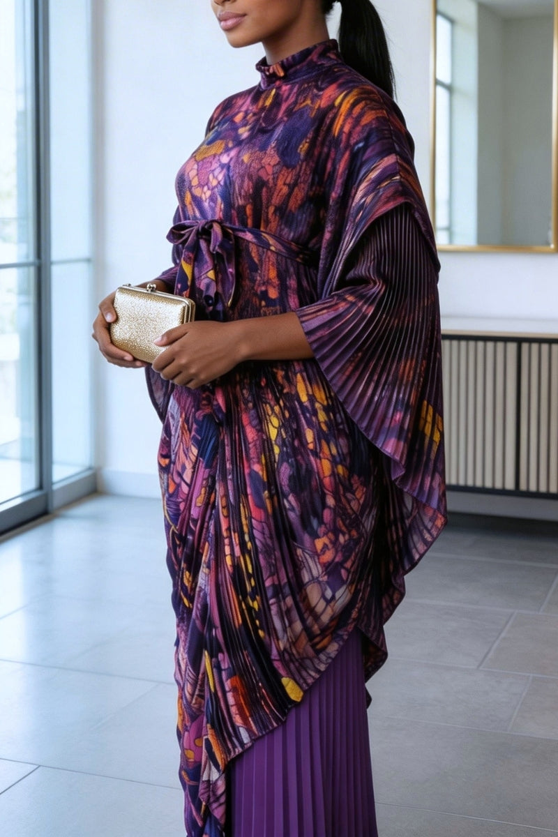 Woman wearing a colorful, patterned dress holding a gold clutch in an indoor setting.